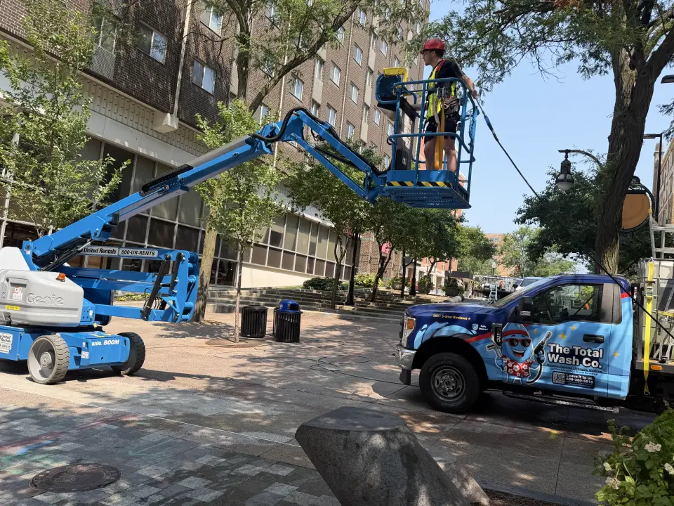 A technician on a boom lift cleaning the exterior of a commercial building