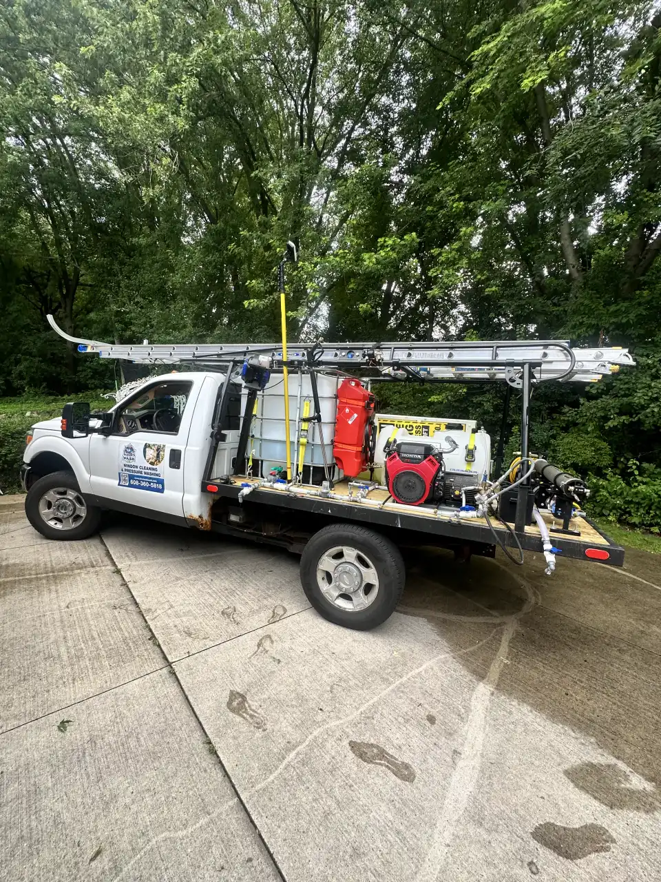 A Total Wash Co. flatbed truck loaded with pressure-washing equipment parked on a residential driveway