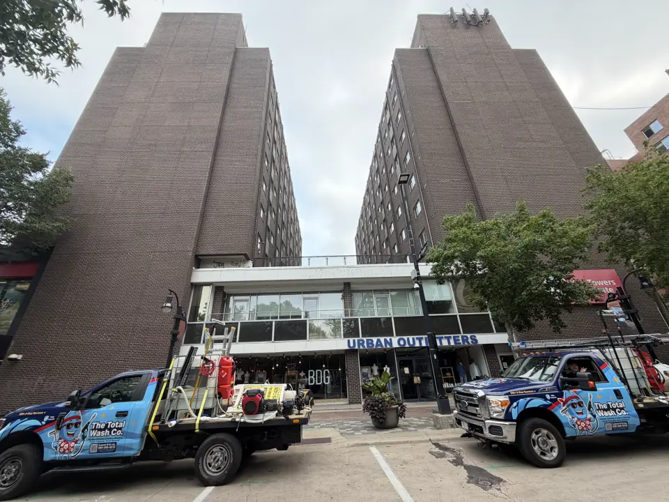 Two Total Wash Co. trucks parked outside a large commercial building
